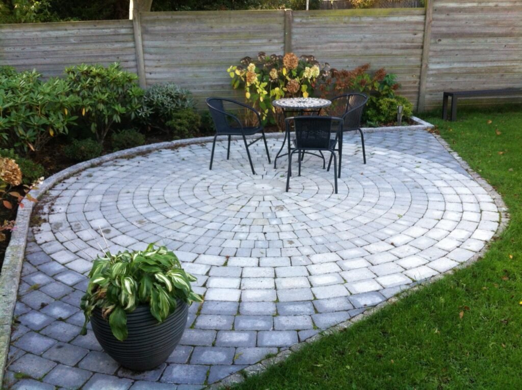 Rund terrasse med bord og stole i haven