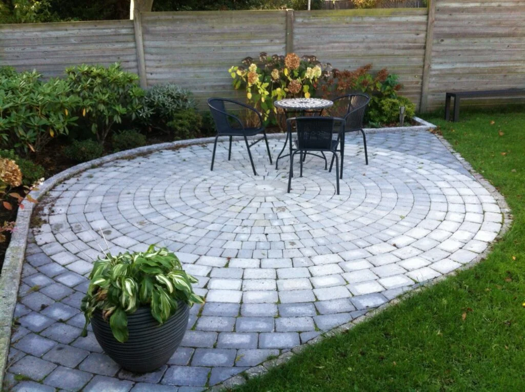 Rund terrasse med bord og stole i haven