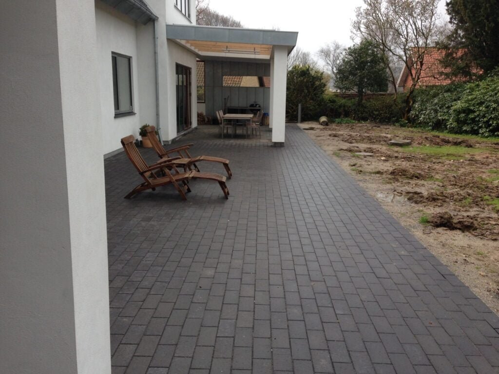 Moderne terrasse med sorte fliser og liggestole