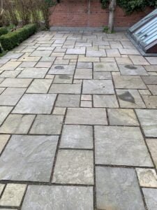 Flisebelagt terrasse foran murstensvæg og have