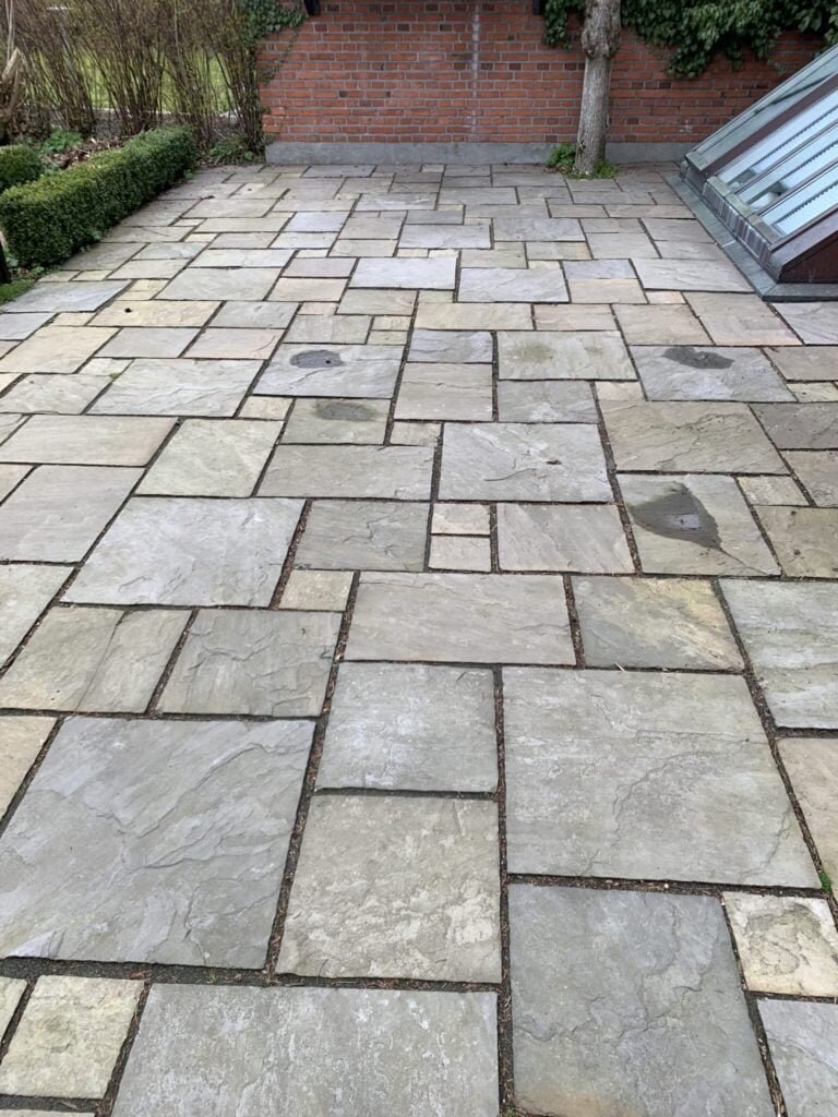 Flisebelagt terrasse foran murstensvæg og have