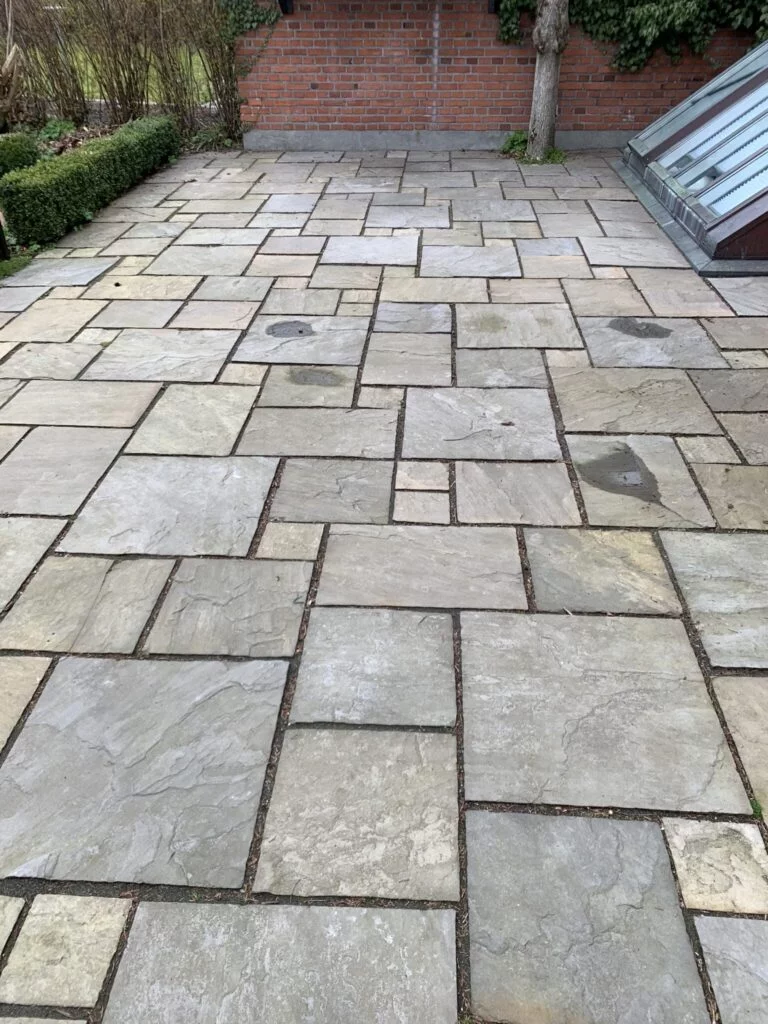 Flisebelagt terrasse foran murstensvæg og have